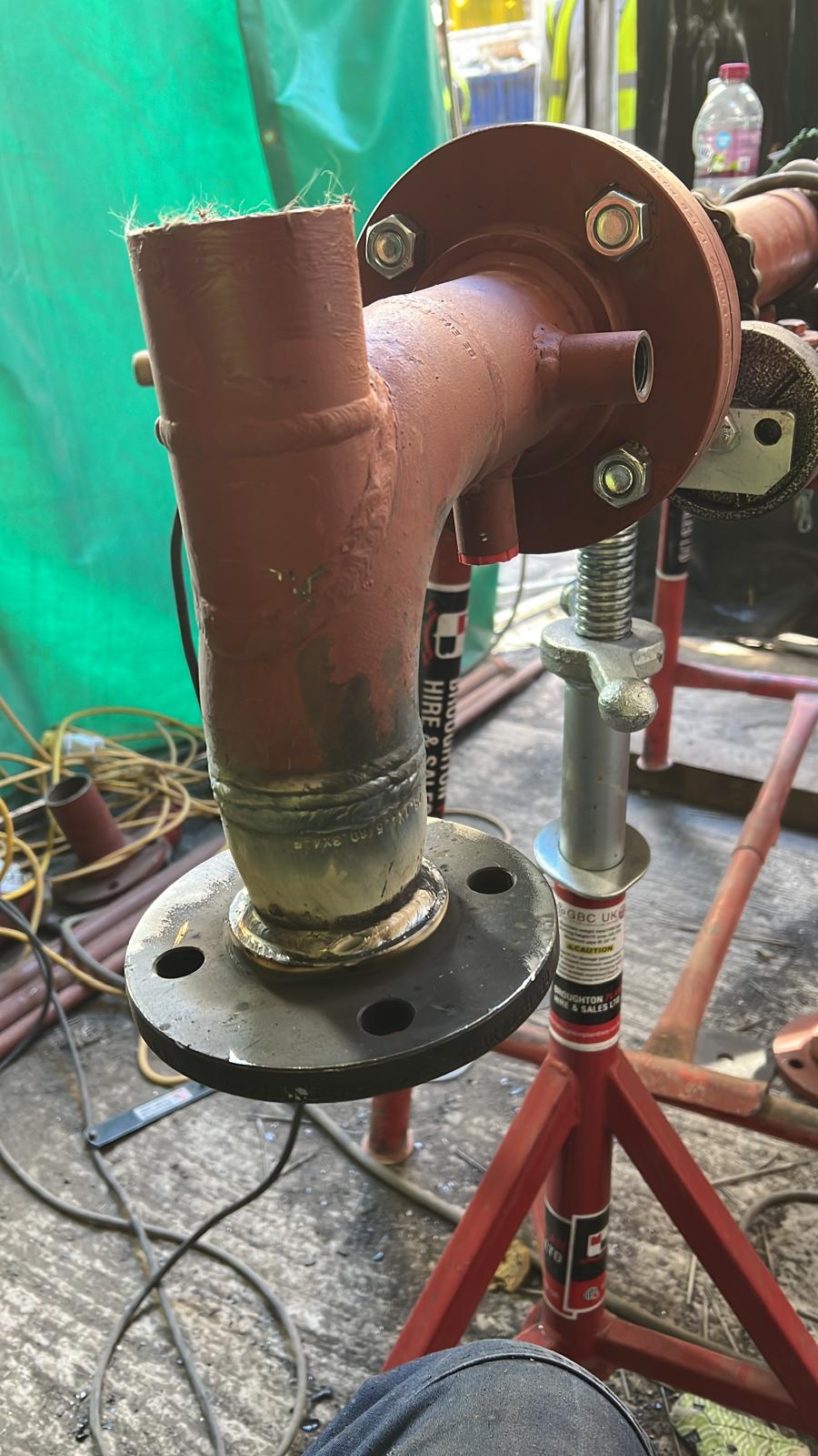 Red painted pipe fabrication on roller stand
